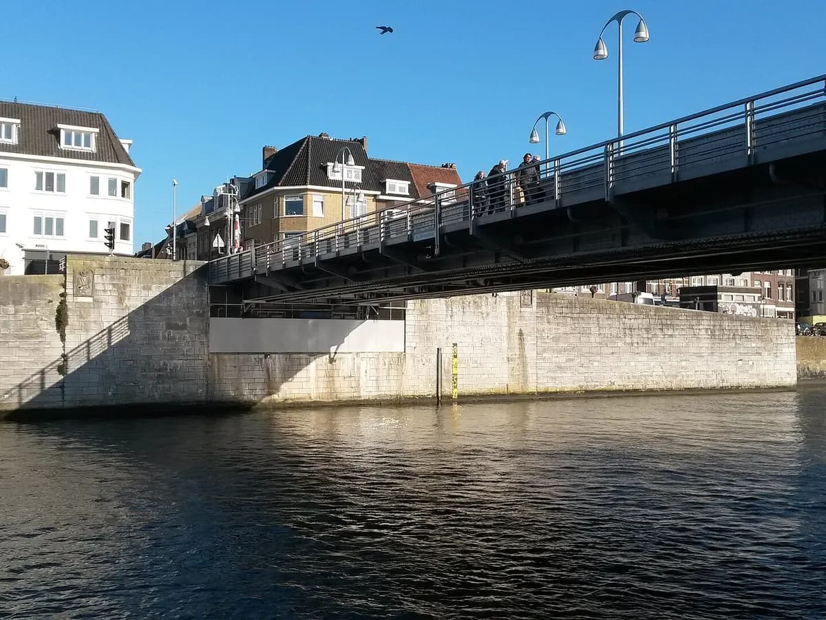 Maastricht: een middeleeuwse boogbrug over de Maas met voetgangers erop