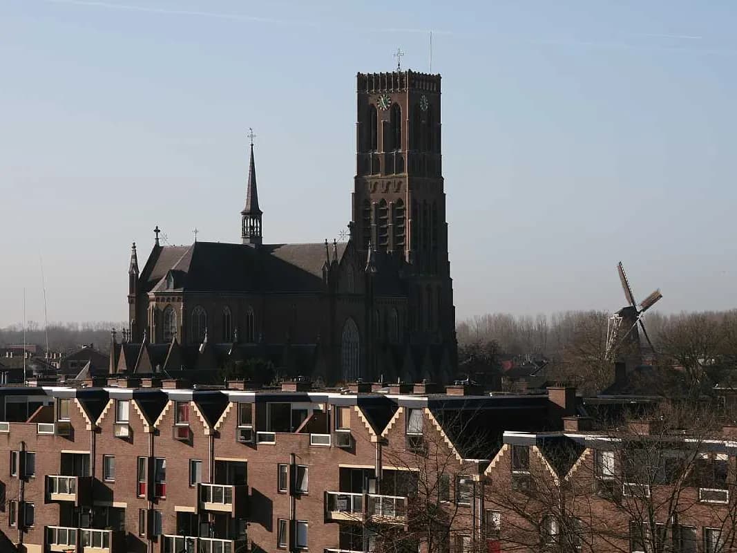 Oss: een neogotische kerk met een hoge spits boven de stad