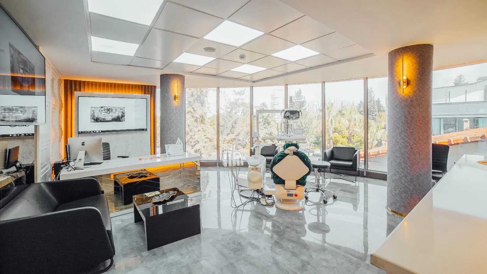 Een hoekbehandelkamer van Ballıpınar Dental met ramen tot de vloer aan twee zijden en röntgenbeelden op een wandscherm
